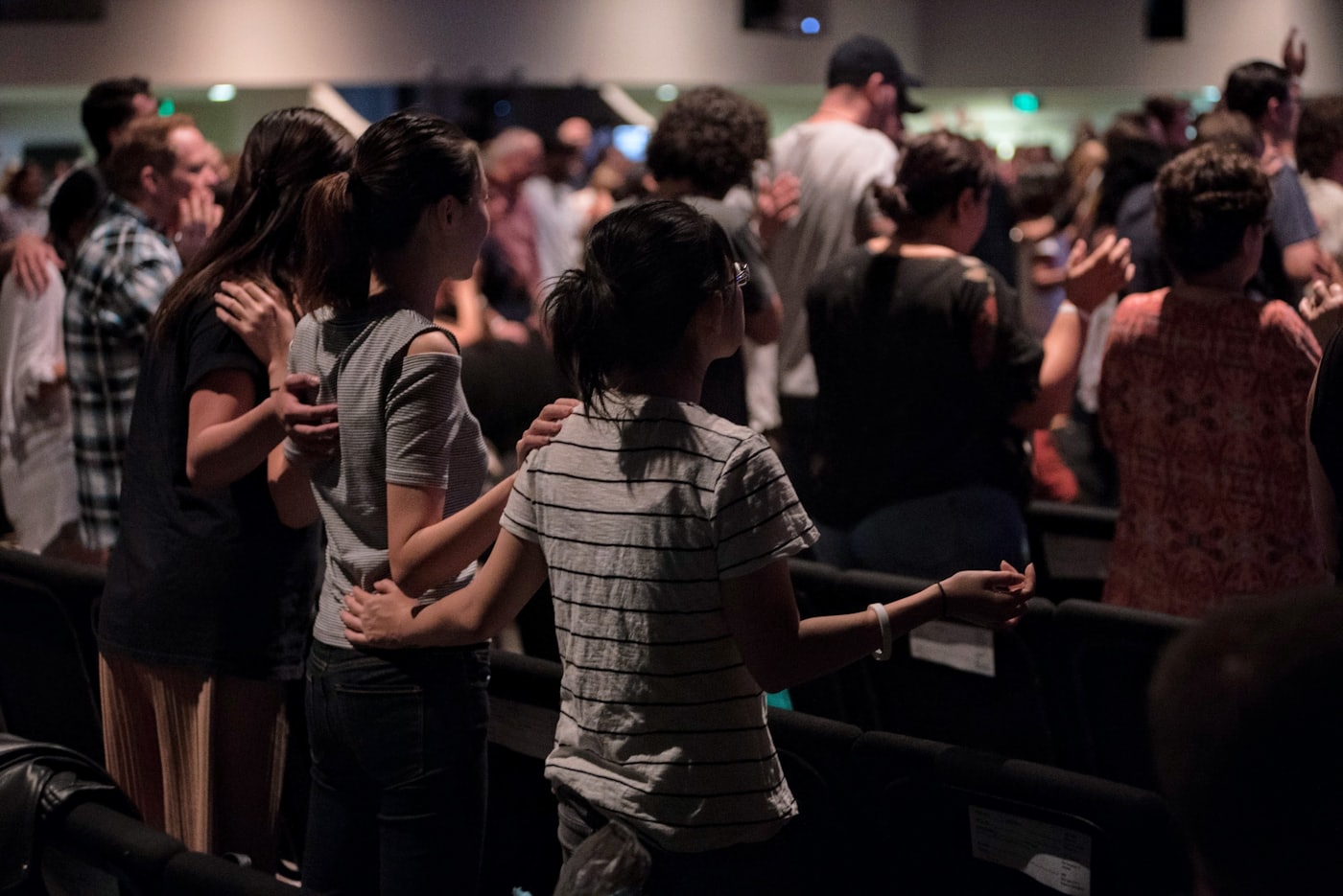 People standing together with hands on one another's shoulders during a church service