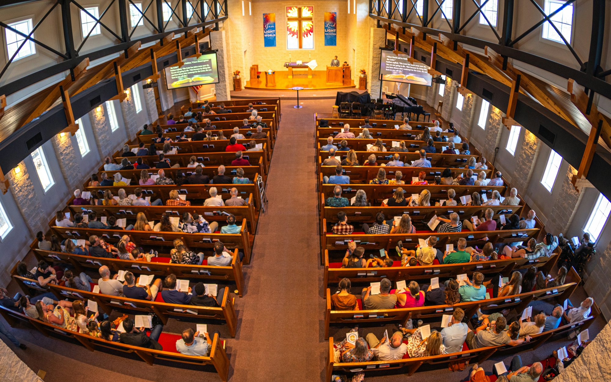 A congregation seated in pews during a Sunday service, seen from the balcony