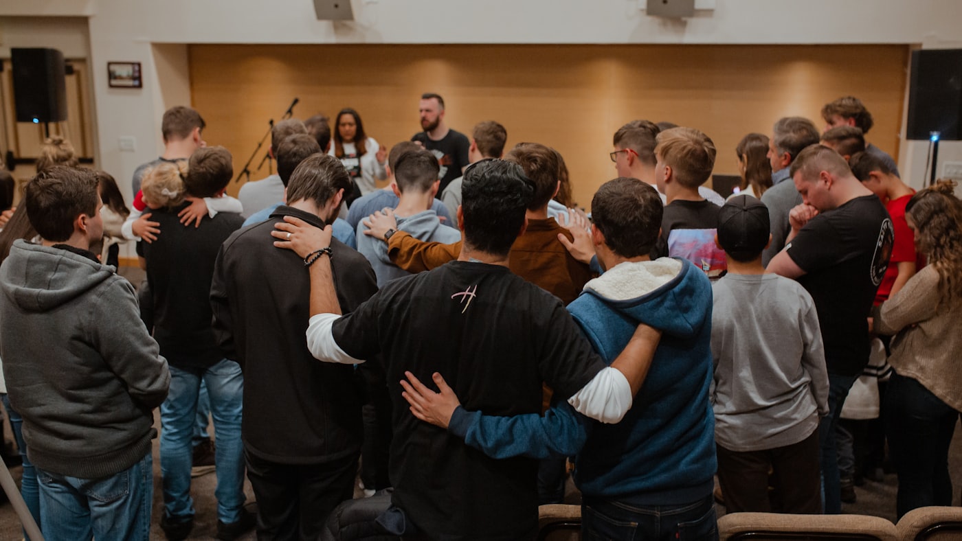 A circle of church volunteers praying together with hands on shoulders