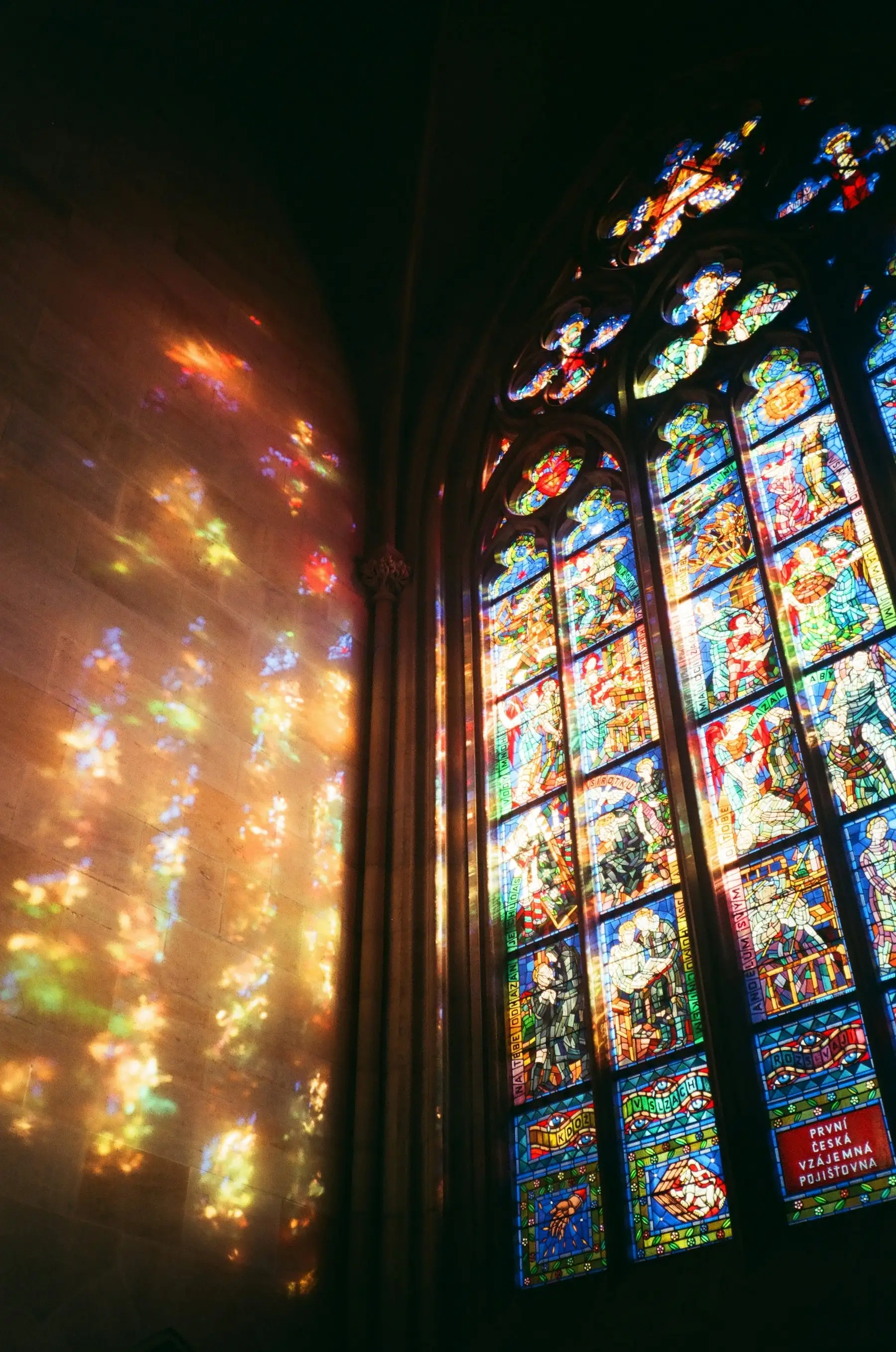 Light through a stained glass window falling in colour across a stone wall